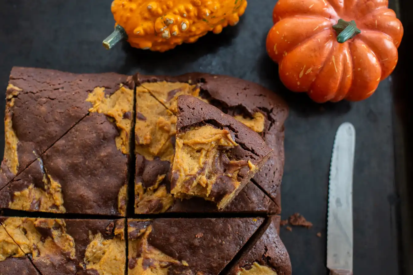 Brownie dyniowe pokrojone na kawałki z dekoracyjnymi dyniami obok